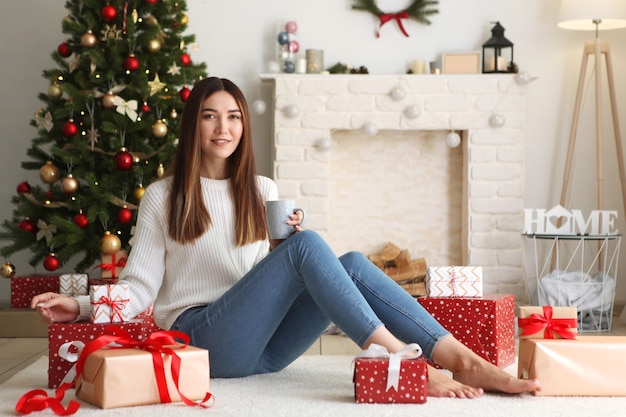 Mulher jovem e bonita em um interior de natal com lugar de presentes para texto