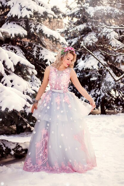 Mulher jovem e bonita em um lindo vestido longo na floresta de inverno