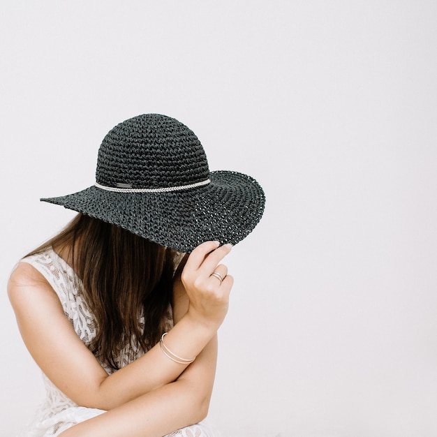 Mulher jovem e bonita em um vestido branco com chapéu preto