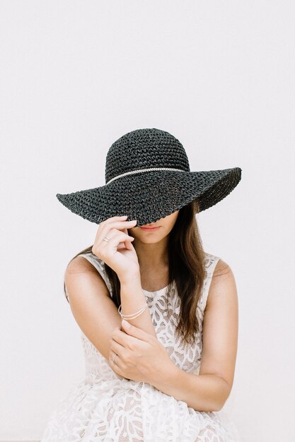 Mulher jovem e bonita em um vestido branco com chapéu preto