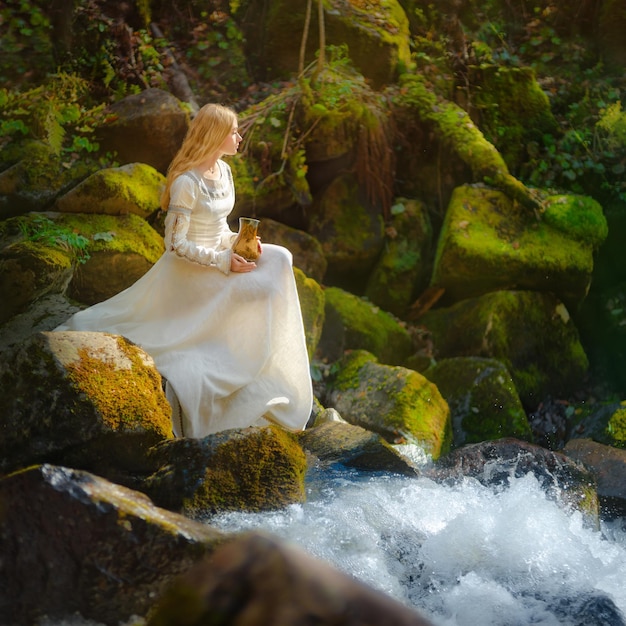 Mulher jovem e bonita em um vestido branco no meio de uma floresta