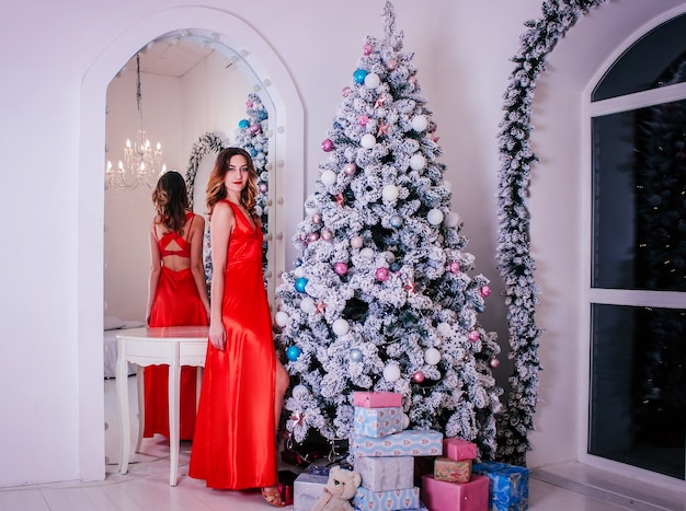 Mulher jovem e bonita em um vestido vermelho closeup com enfeites de Natal