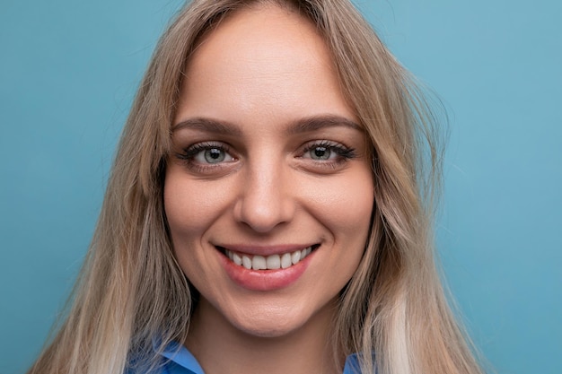 Mulher jovem e bonita em uma camisa azul sorrindo alegremente sobre um fundo azul