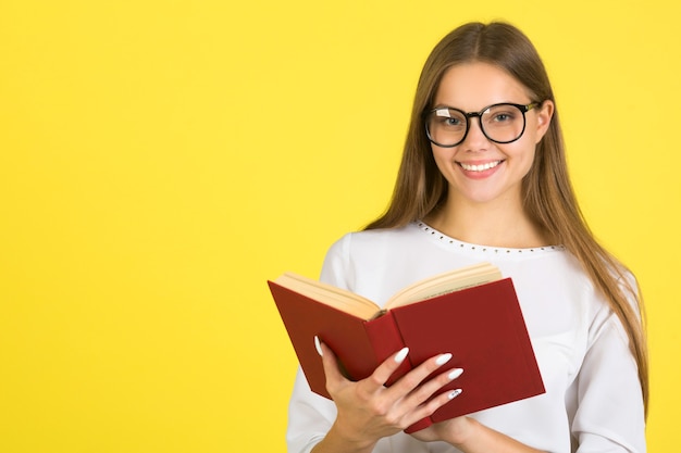 Mulher jovem e bonita em uma camisa branca sobre um fundo amarelo