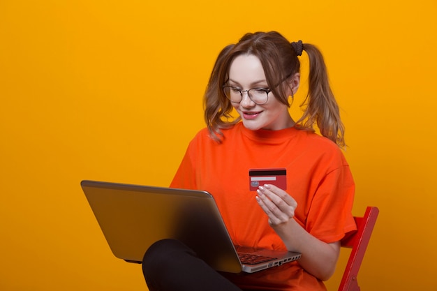 Foto mulher jovem e bonita em uma camiseta com um laptop