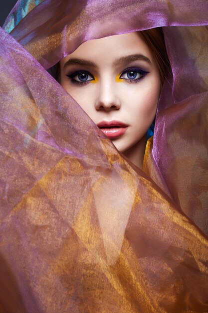 Mulher jovem e bonita em véu colorido garota de maquiagem colorida
