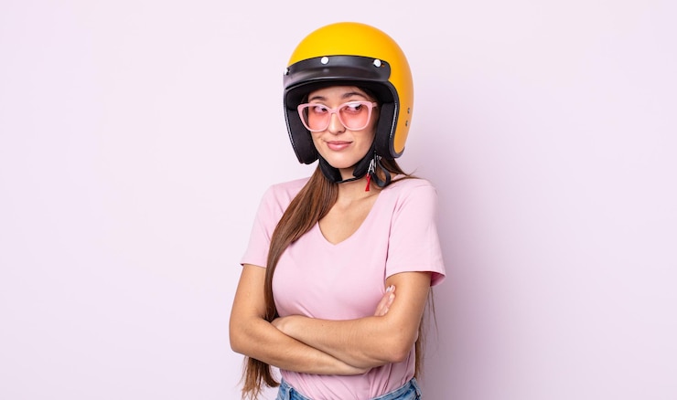 Foto mulher jovem e bonita encolhendo os ombros, sentindo-se confusa e incerta. piloto de moto e capacete