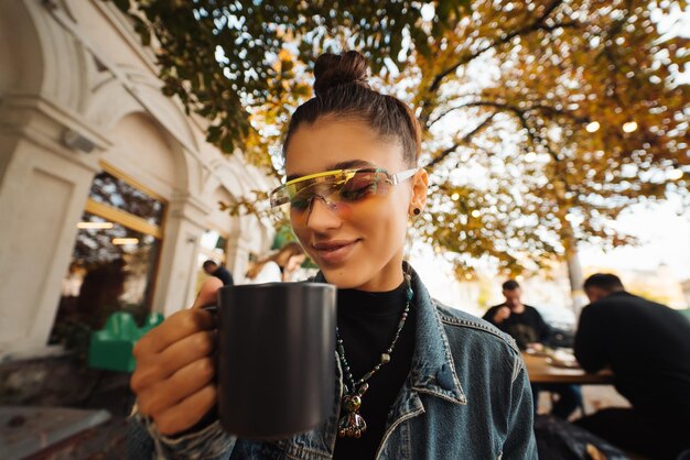 Mulher jovem e bonita enquanto bebe chá no moderno café de rua