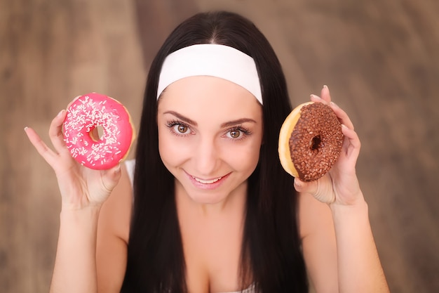 Mulher jovem e bonita escolhendo entre maçã e donut