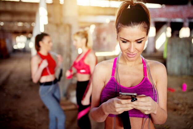 Mulher jovem e bonita escutando música treino de treino de fitness. grupo de pessoas de aptidão por trás da preparação para o treinamento.