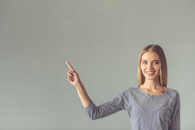 Mulher jovem e bonita está apontando para longe.