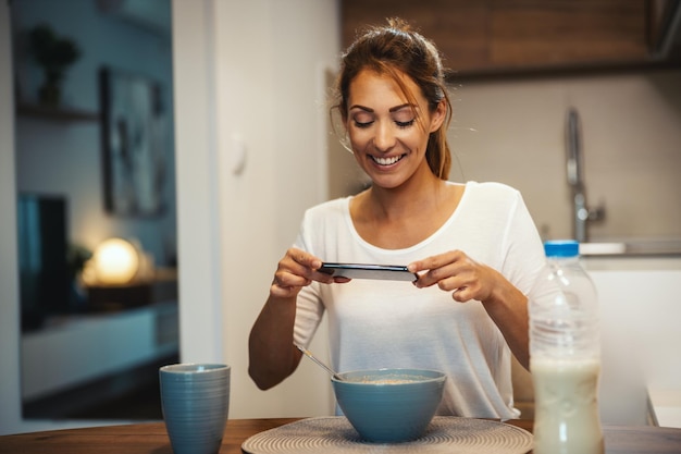 Mulher jovem e bonita está filmando sua transmissão de blog sobre comida saudável em casa.