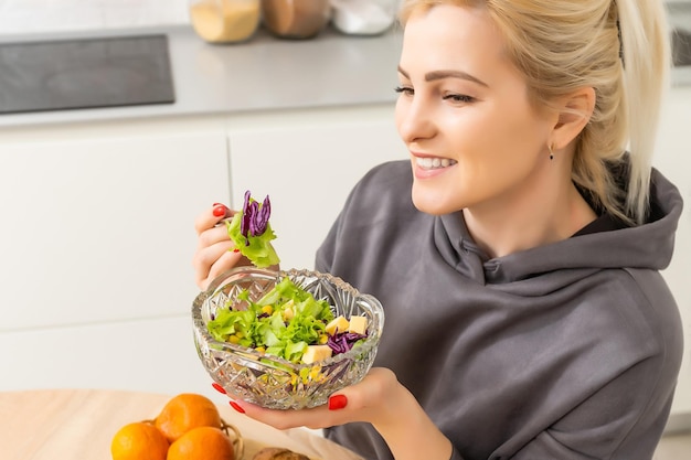 Mulher jovem e bonita está preparando salada de legumes na cozinha. Cozinhar Em Casa.