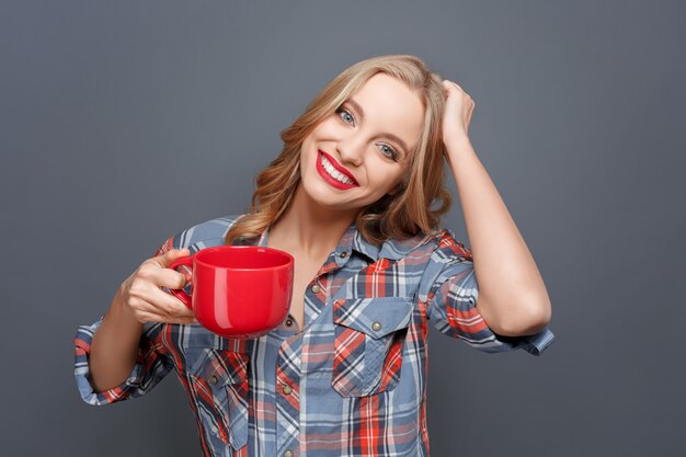 Mulher jovem e bonita está segurando um copo vermelho na mão direita