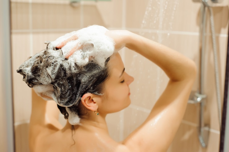 Foto mulher jovem e bonita está sorrindo e usando shampoo