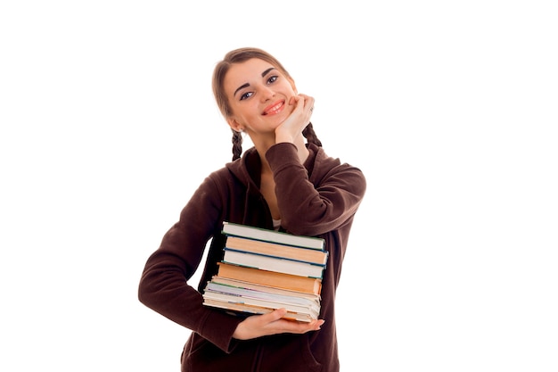 Mulher jovem e bonita estudante com muitos livros nas mãos, posando isolada em uma parede branca em um estúdio