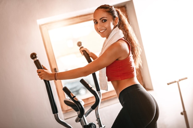 Mulher jovem e bonita exercitando em stepper em casa.