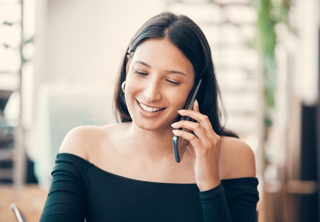 Mulher jovem e bonita falando em um telefonema sentado sozinho em um café Mulher confiante e amigável flertando e sorrindo enquanto liga para alguém do lado de fora de um restaurante em um fim de semana de verão