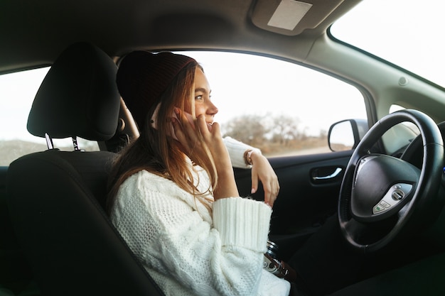 Mulher jovem e bonita falando no celular enquanto está sentado em um carro