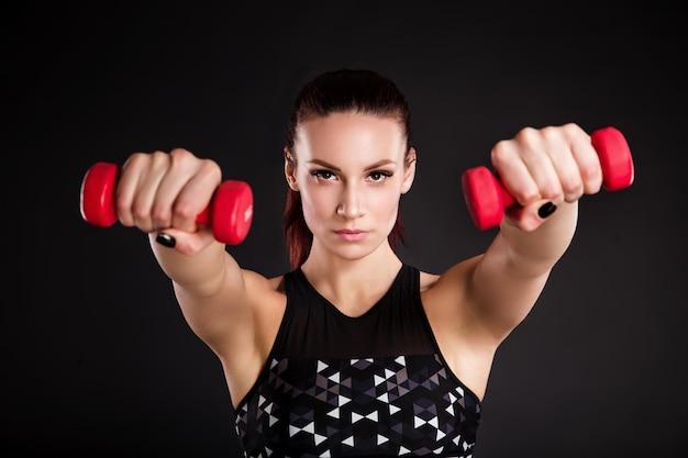 Foto mulher jovem e bonita fazendo exercícios com halteres foto mulher atlética com corpo perfeito em fundo preto força e motivação