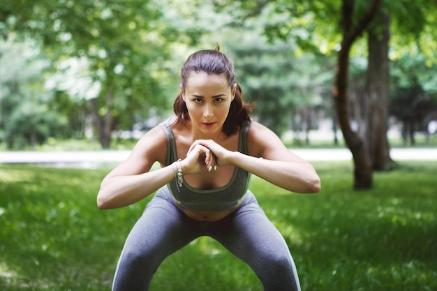 Mulher jovem e bonita fazendo exercícios de ioga em um parque verde