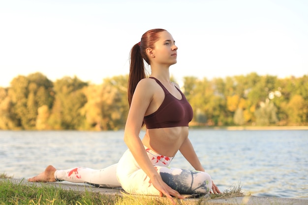 Mulher jovem e bonita fazendo exercícios de ioga no parque.