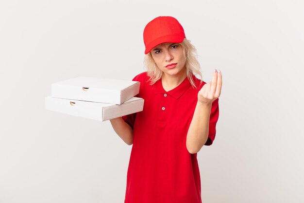Mulher jovem e bonita fazendo gesto de capice ou dinheiro, dizendo para você pagar. conceito de entrega de pizza