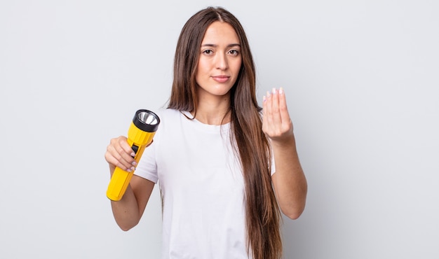 Mulher jovem e bonita fazendo gesto de capice ou dinheiro, dizendo para você pagar. conceito de lanterna