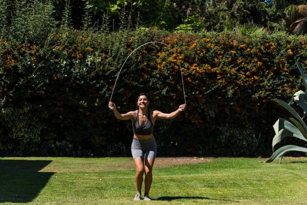 Mulher jovem e bonita fazendo ginástica no jardim de sua casa