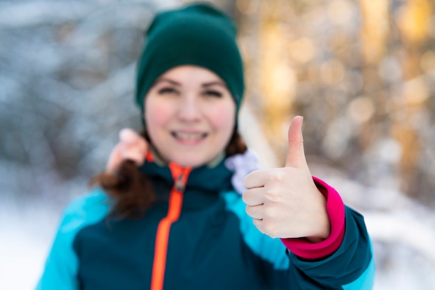 Mulher jovem e bonita feliz está ao ar livre em um dia frio de sol de inverno em um parque nevado ou