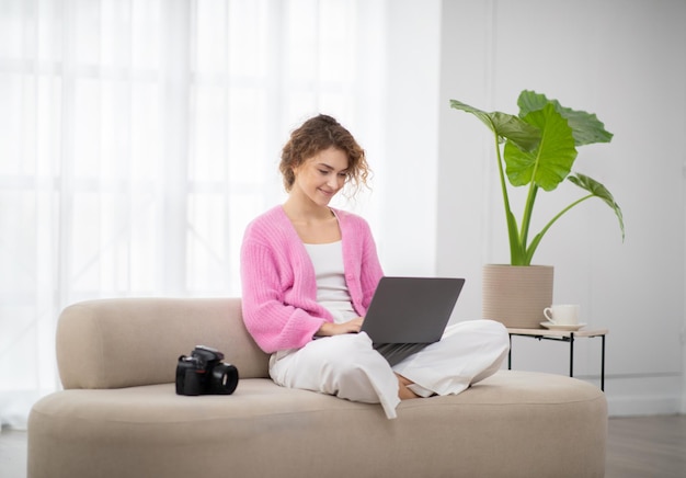 Mulher jovem e bonita fotógrafa usando laptop em casa retocando fotos