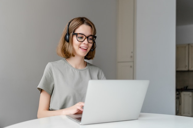 Mulher jovem e bonita Freelancer olhando para o computador portátil com fone de ouvido. Trabalho freelance, funcionário do call center