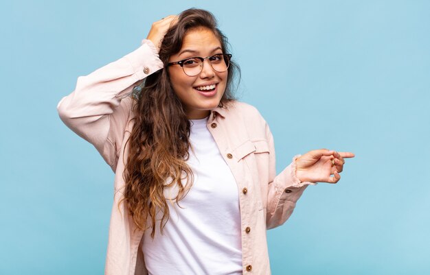 Mulher jovem e bonita gesticulando na parede azul