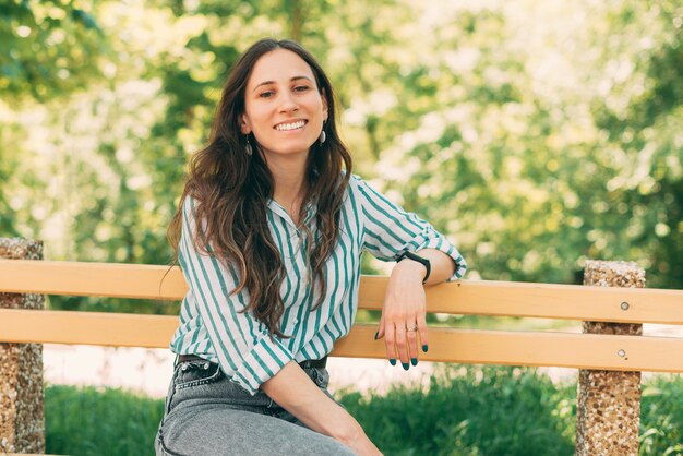 Mulher jovem e bonita gosta de passeios ao ar livre e senta-se no parque.