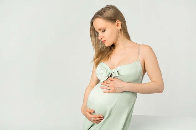 Mulher jovem e bonita grávida com um vestido em um fundo branco