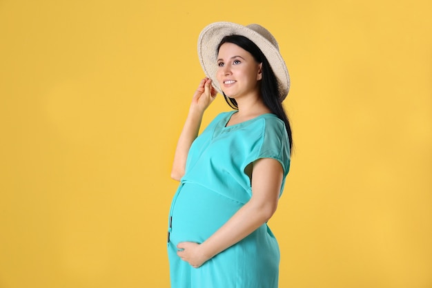 Mulher jovem e bonita grávida em um vestido azul na parede amarela