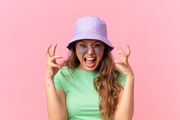 Mulher jovem e bonita gritando com as mãos no ar. conceito de verão