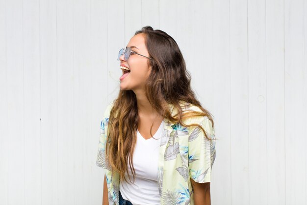 Mulher jovem e bonita gritando furiosamente, gritando agressivamente, parecendo estressada e com raiva