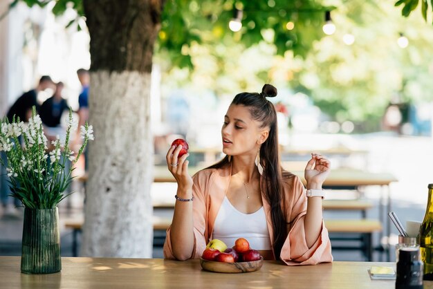 Mulher jovem e bonita hipster sentada no café da varanda na rua