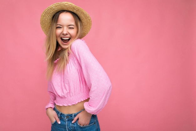 Mulher jovem e bonita loira sorrindo e se divertindo em pé, isolada na parede rosa, de mãos dadas