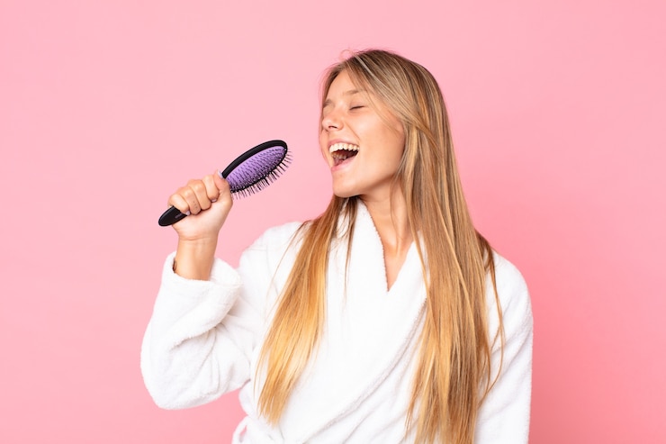 Foto mulher jovem e bonita loira usando roupão de banho e segurando uma escova de cabelo