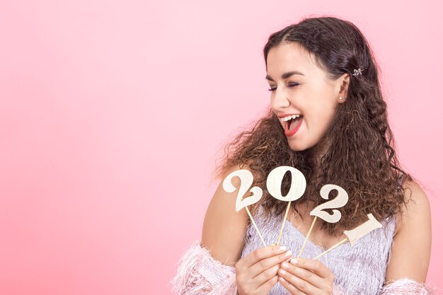 Mulher jovem e bonita morena elegante com cabelo encaracolado e ombros nus segurando um número de madeira para o conceito de ano novo