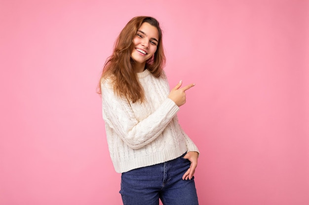 Mulher jovem e bonita morena elegante europeia vestindo uma camisola branca de inverno isolada sobre o rosa