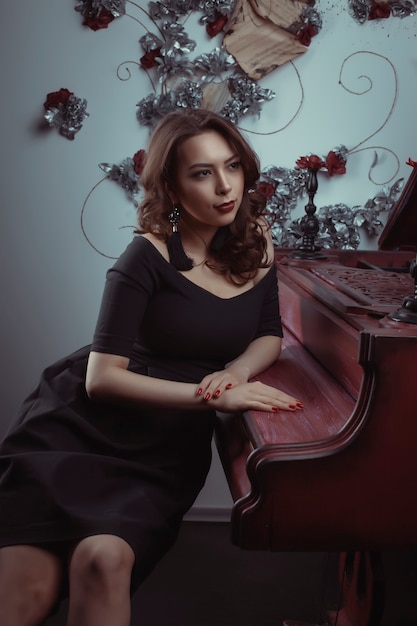 Mulher jovem e bonita morena sentada ao piano no estúdio