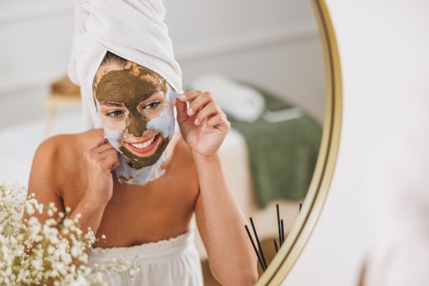 Mulher jovem e bonita na frente do espelho removendo a máscara facial no salão de beleza.