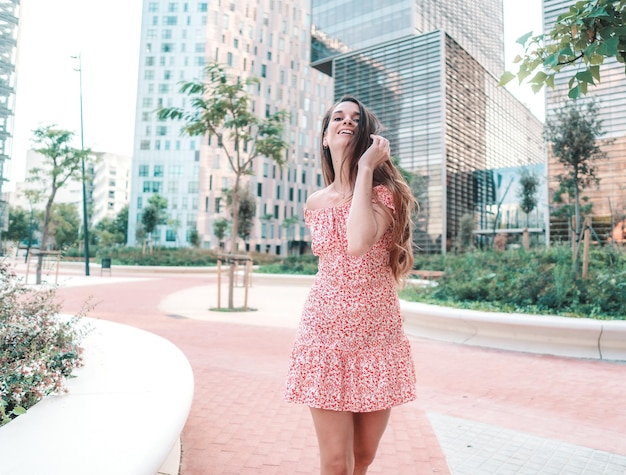 Mulher jovem e bonita na moda em um vestido elegante sexy, posando na cidade moderna com arranha-céus no fundo.