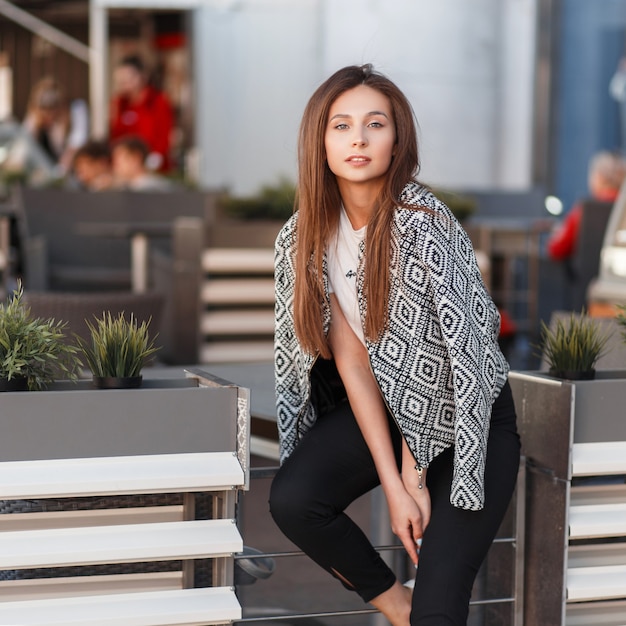 Mulher jovem e bonita na moda jaqueta com um padrão na cidade em um dia ensolarado