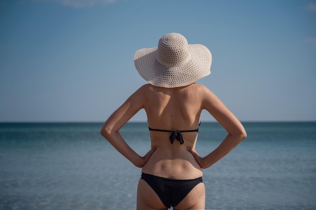 Mulher jovem e bonita na praia usando chapéu