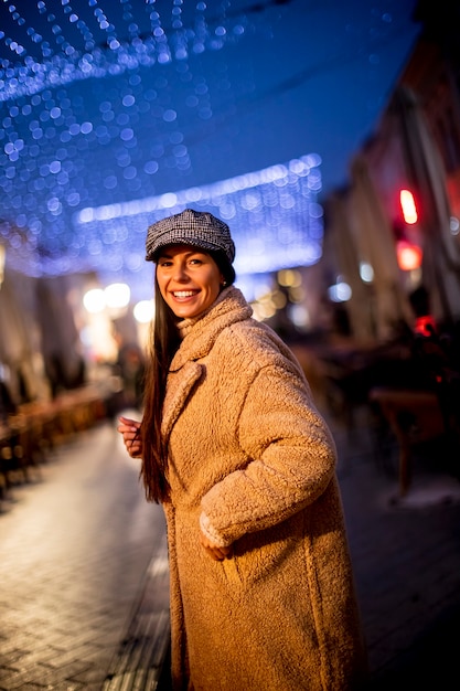 Mulher jovem e bonita na rua na fria noite de Natal