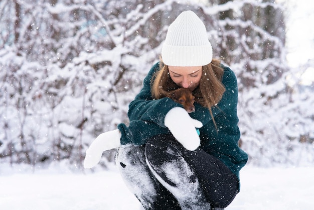 Mulher jovem e bonita no inverno Aquece o cachorro no frio. Menina na neve com um animal de estimação Chihuahua, congelou.